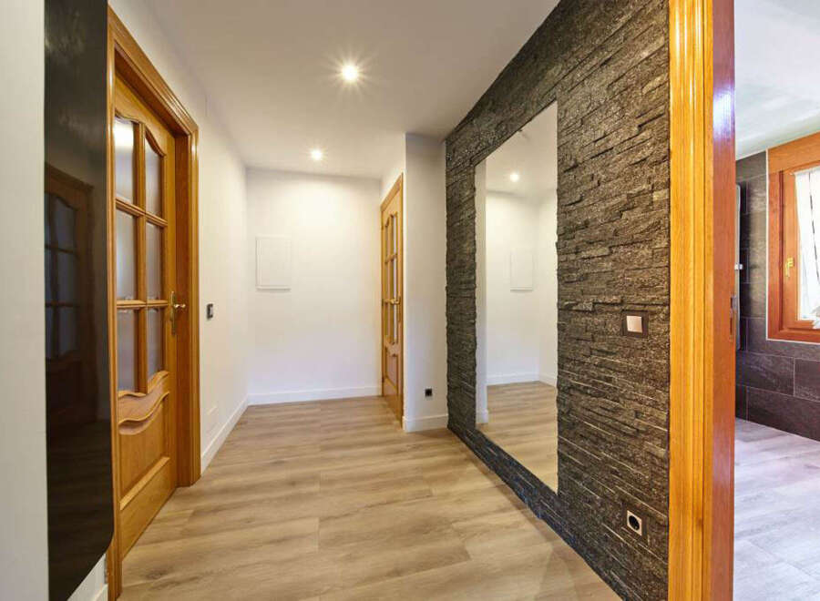 This stunning hallway boasts a modern design with sleek flooring and a beautiful stone accent wall.