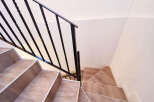 Modern staircase with sleek black metal railing and light wood flooring.