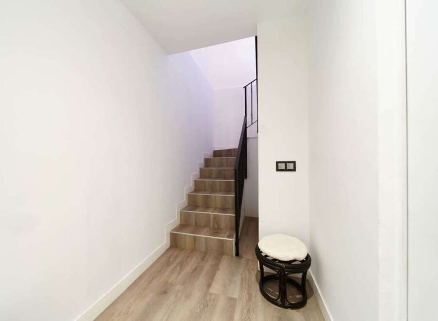 Modern hallway with stylish wooden flooring and a contemporary staircase leading upstairs.