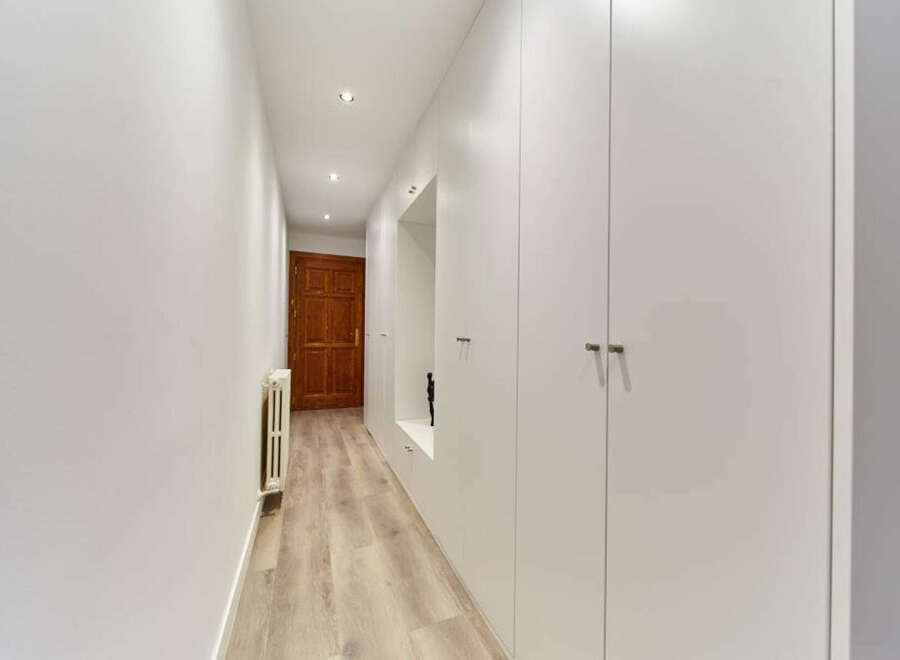 This stunning hallway boasts built-in white wardrobes, offering ample storage space.