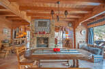 Rustic mountain chalet with a stunning stone fireplace, wooden beams, and large windows offering breathtaking views.