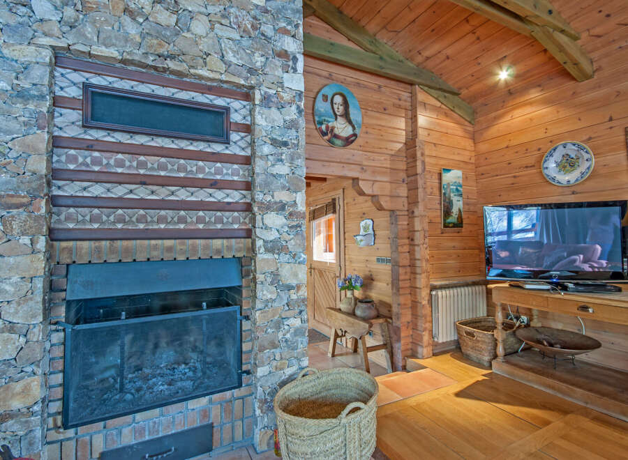 Rustic mountain cabin with a stunning stone fireplace, wood-beamed ceilings, and hardwood floors.