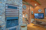 Rustic mountain cabin with a stunning stone fireplace, wood-beamed ceilings, and hardwood floors.