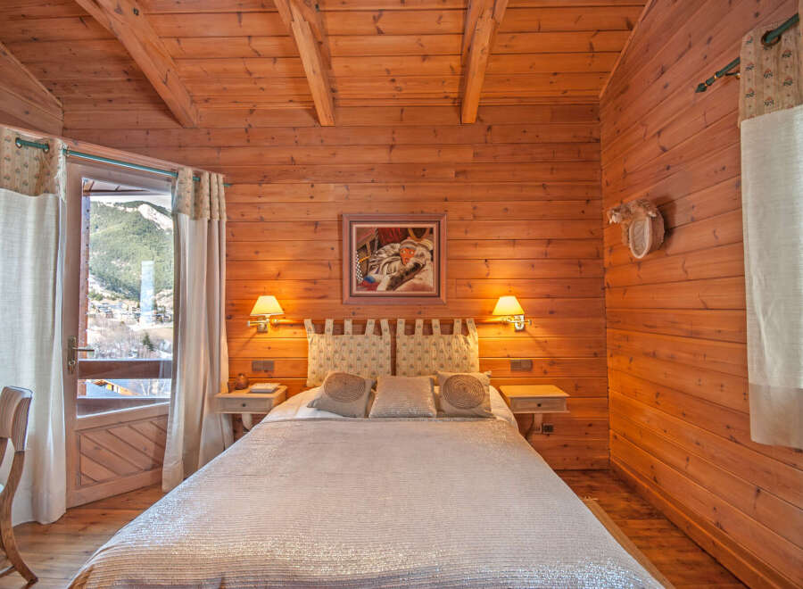 Cozy wooden cabin bedroom with mountain views.