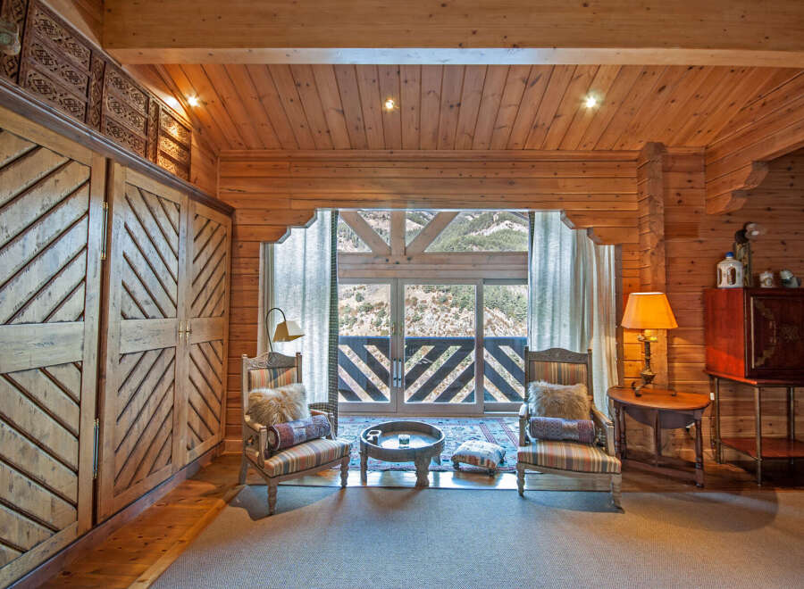 This stunning log cabin boasts a spacious bedroom with a cozy sitting area, perfect for relaxing and enjoying the breathtaking mountain views.