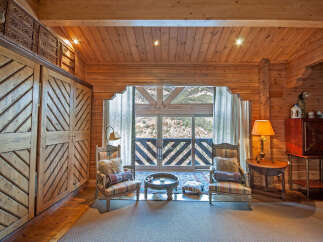 This stunning log cabin boasts a spacious bedroom with a cozy sitting area, perfect for relaxing and enjoying the breathtaking mountain views.