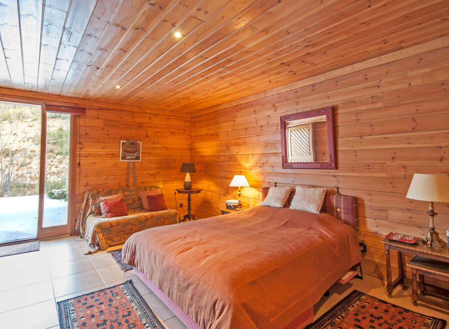 Cozy wooden cabin bedroom with a comfy bed and stunning mountain views.