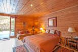 Cozy wooden cabin bedroom with a comfy bed and stunning mountain views.