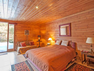 Cozy wooden cabin bedroom with a comfy bed and stunning mountain views.