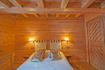 Cozy wooden cabin bedroom with a comfortable bed and warm lighting.