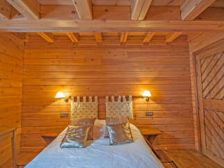 Cozy wooden cabin bedroom with a comfortable bed and warm lighting.