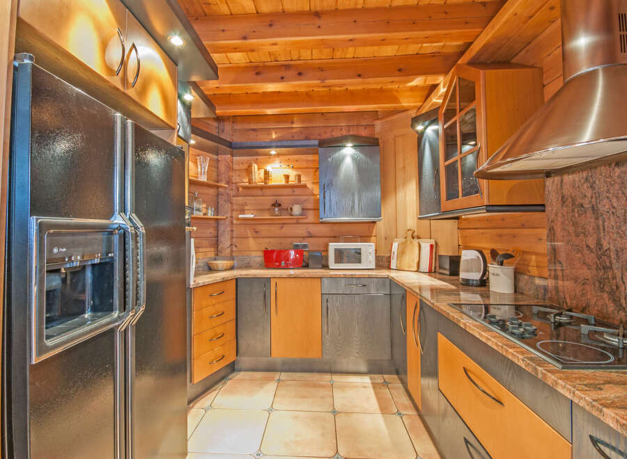 This stunning kitchen boasts a unique blend of modern and rustic design, featuring sleek black appliances and rich wood cabinetry.