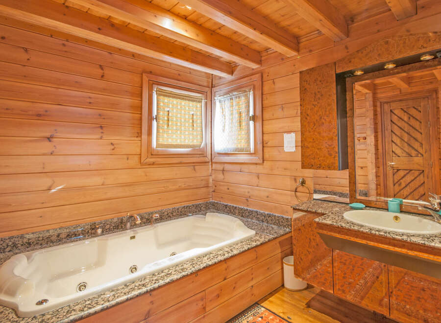 Luxurious wooden bathroom with jacuzzi tub and granite countertop.
