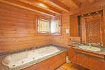 Luxurious wooden bathroom with jacuzzi tub and granite countertop.