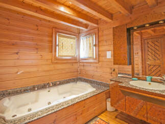 Luxurious wooden bathroom with jacuzzi tub and granite countertop.