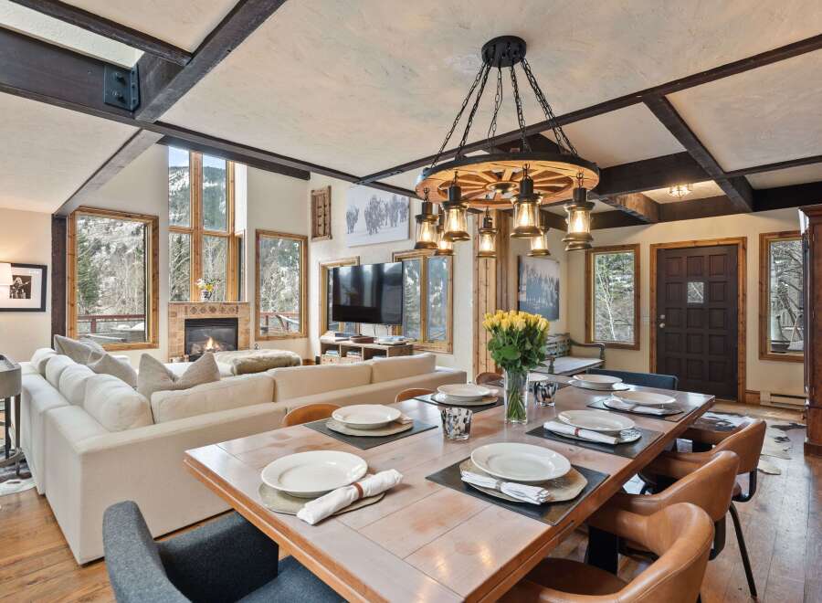 This stunning mountain home boasts an open-concept living area with floor-to-ceiling windows offering breathtaking views, a cozy fireplace, and a spacious dining area perfect for entertaining.