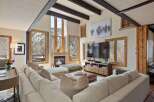 This stunning living room boasts a spacious sectional sofa, perfect for relaxing by the fireplace and enjoying the breathtaking mountain views through expansive windows.