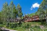 Luxury mountain homes nestled in a lush aspen grove, offering stunning views and private decks.