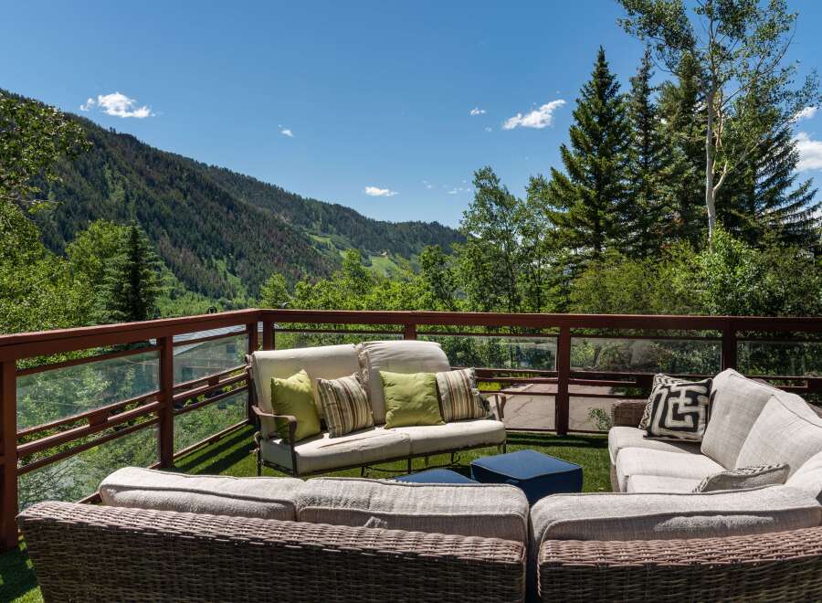 Enjoy breathtaking mountain views from this luxurious deck, complete with comfortable wicker furniture and plush cushions.