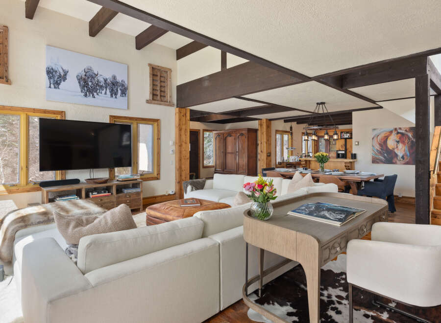 This stunning vacation rental boasts an open-concept living area with a cozy sectional sofa, a large flat-screen TV, and a beautiful wooden coffee table.