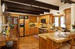 This charming kitchen boasts rustic wooden cabinetry, exposed beams, and a large island with seating, creating a warm and inviting atmosphere.