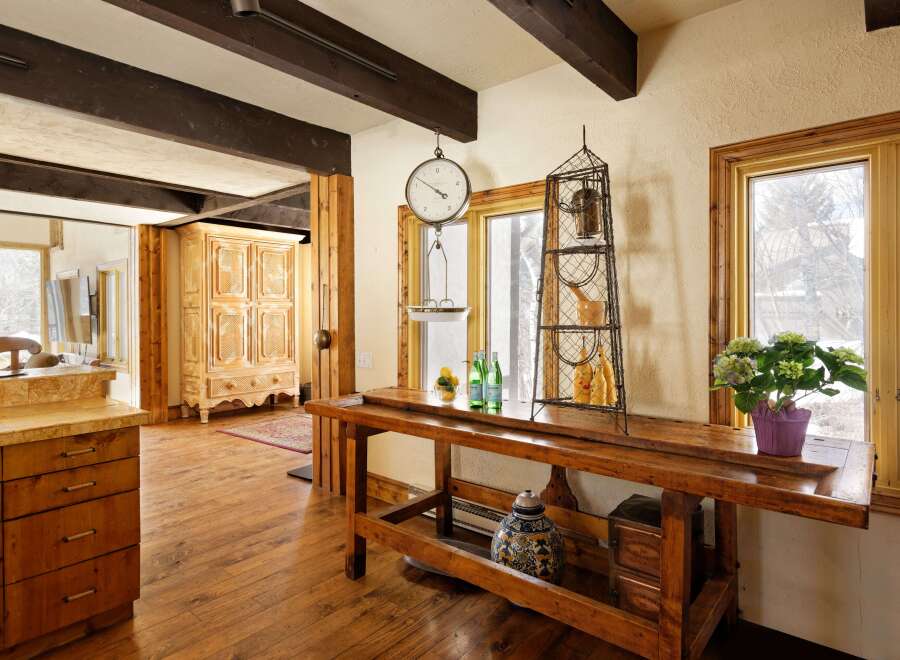 Rustic kitchen features exposed wooden beams, hardwood floors, and a vintage wooden workbench island.