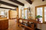 Rustic kitchen features exposed wooden beams, hardwood floors, and a vintage wooden workbench island.