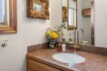 This charming bathroom boasts a vintage-style brass faucet and an oval sink, complemented by a granite countertop and wooden cabinetry.
