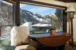 Mountain view home boasts a stunning vista through expansive windows, showcasing snow-capped peaks and a lush green lawn.