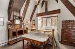 This charming bedroom boasts a unique blend of rustic and antique features, highlighted by exposed wooden beams and a brass bed frame.
