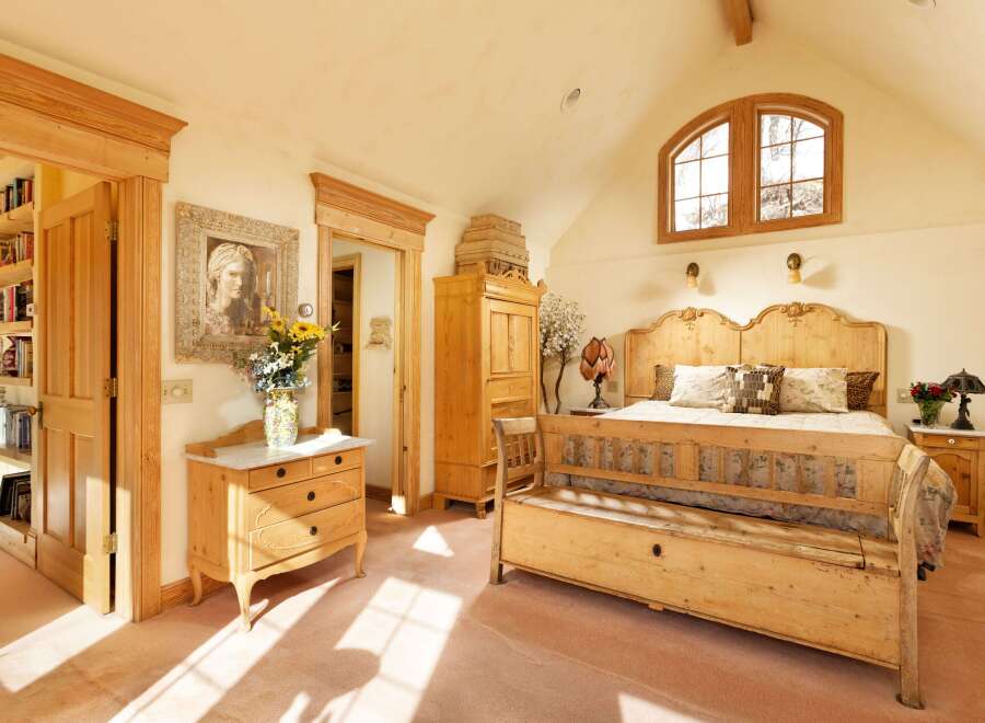 This charming bedroom boasts a light and airy feel, thanks to its vaulted ceiling and large arched window.