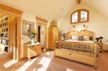 This charming bedroom boasts a light and airy feel, thanks to its vaulted ceiling and large arched window.
