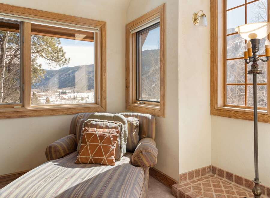 Relax and enjoy the breathtaking mountain views from this cozy chaise lounge, perfectly positioned in front of large windows.
