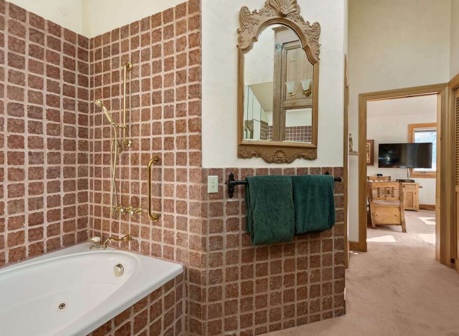 This luxurious bathroom boasts a spacious jacuzzi tub, a rainfall showerhead, and elegant gold-toned fixtures.