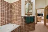 This luxurious bathroom boasts a spacious jacuzzi tub, a rainfall showerhead, and elegant gold-toned fixtures.