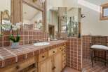 This luxurious bathroom boasts a stunning brick tile design, complemented by elegant wooden cabinetry and ornate mirrors.