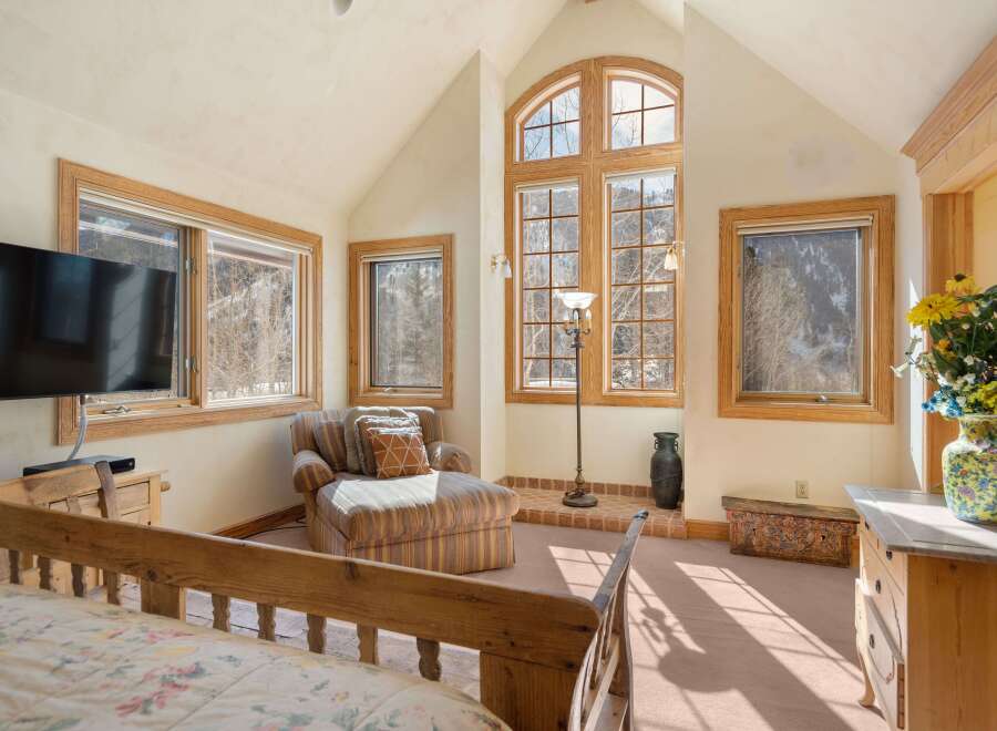 This bright and airy bedroom boasts a vaulted ceiling with large windows offering stunning mountain views.
