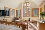 This bright and airy bedroom boasts a vaulted ceiling with large windows offering stunning mountain views.