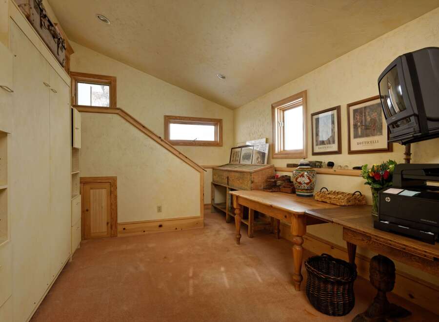 This charming attic room boasts a unique blend of rustic and modern features, including built-in cabinetry, hardwood floors, and large windows that offer ample natural light.