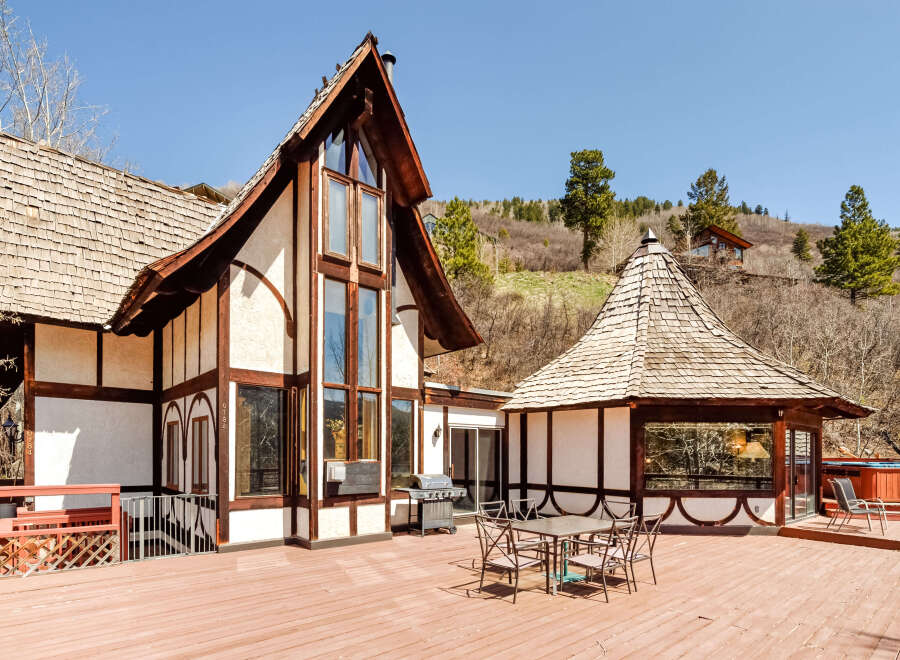 This stunning mountain home boasts a spacious deck with a dining area, grill, and hot tub, perfect for outdoor entertaining.