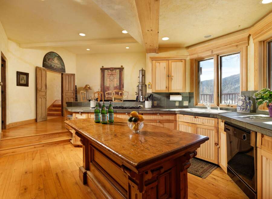 This stunning kitchen boasts a rustic-chic design with exposed wooden beams, a large island, and custom wooden cabinetry.