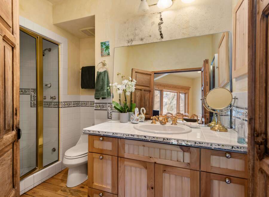 This charming bathroom boasts a rustic-chic design with wood cabinets, white tile, and decorative trim.