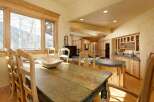 Rustic mountain home boasts a charming kitchen with knotty pine cabinets, a large farmhouse table, and a view of snow-covered trees.