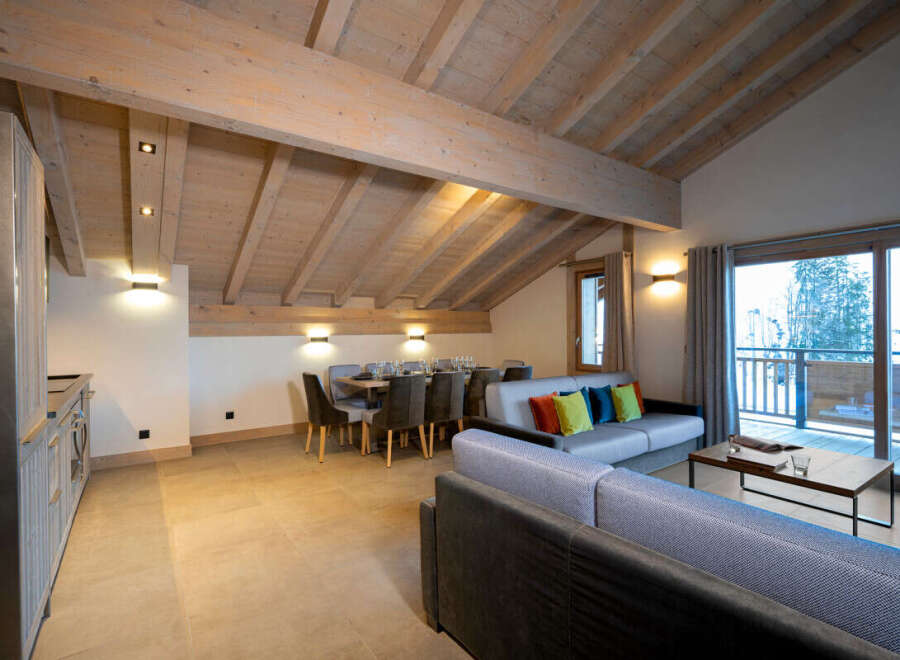 This stunning chalet boasts a spacious open-plan living area with exposed wooden beams, creating a warm and inviting atmosphere.