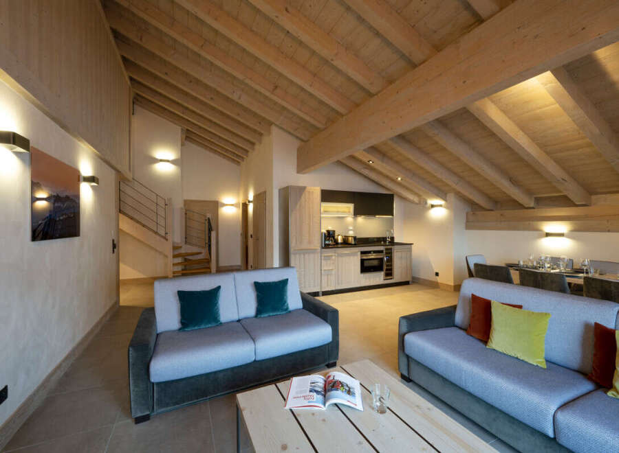This stunning chalet boasts a spacious open-plan living area with exposed wooden beams, creating a warm and inviting atmosphere.