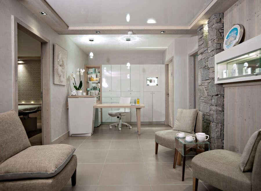 This luxurious spa boasts a serene waiting area with comfortable seating, a sleek reception desk, and modern white cabinetry.