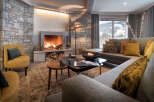 This stunning chalet boasts a cozy living room with a large stone fireplace, perfect for relaxing after a day on the slopes.
