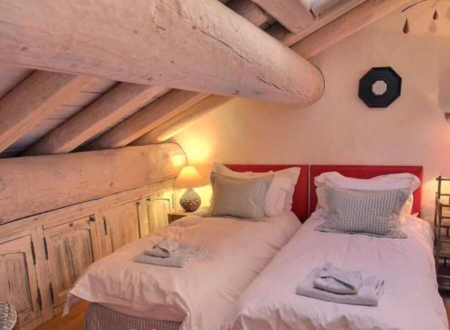 Cozy attic bedroom with twin beds, exposed wooden beams, and rustic charm.