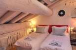 Cozy attic bedroom with twin beds, exposed wooden beams, and rustic charm.