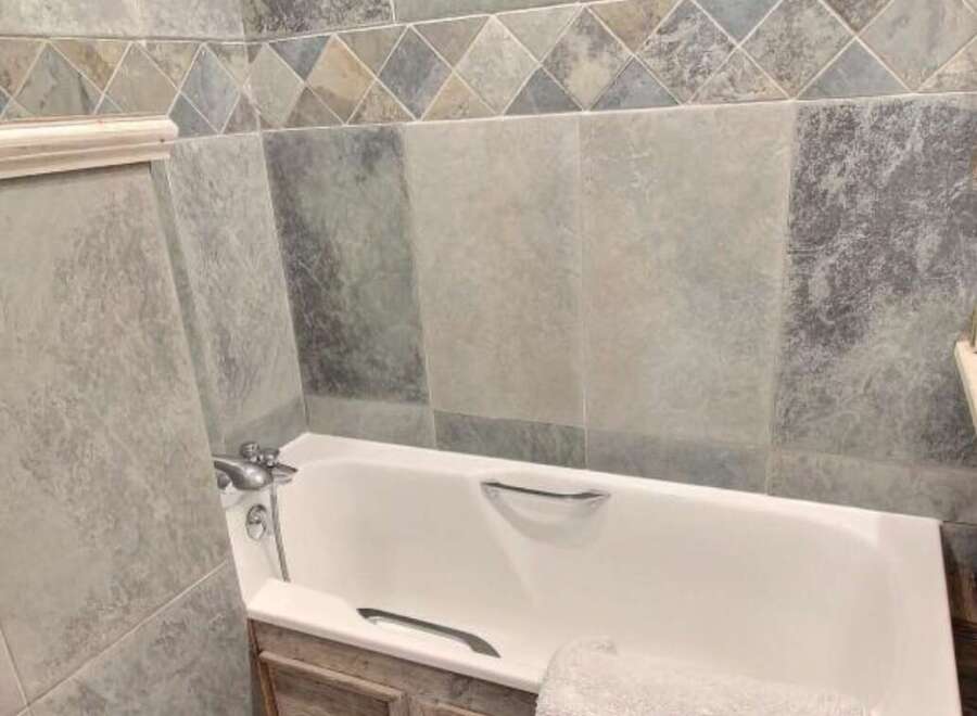 Relax in this charming bathroom featuring a bathtub and stylish tilework.